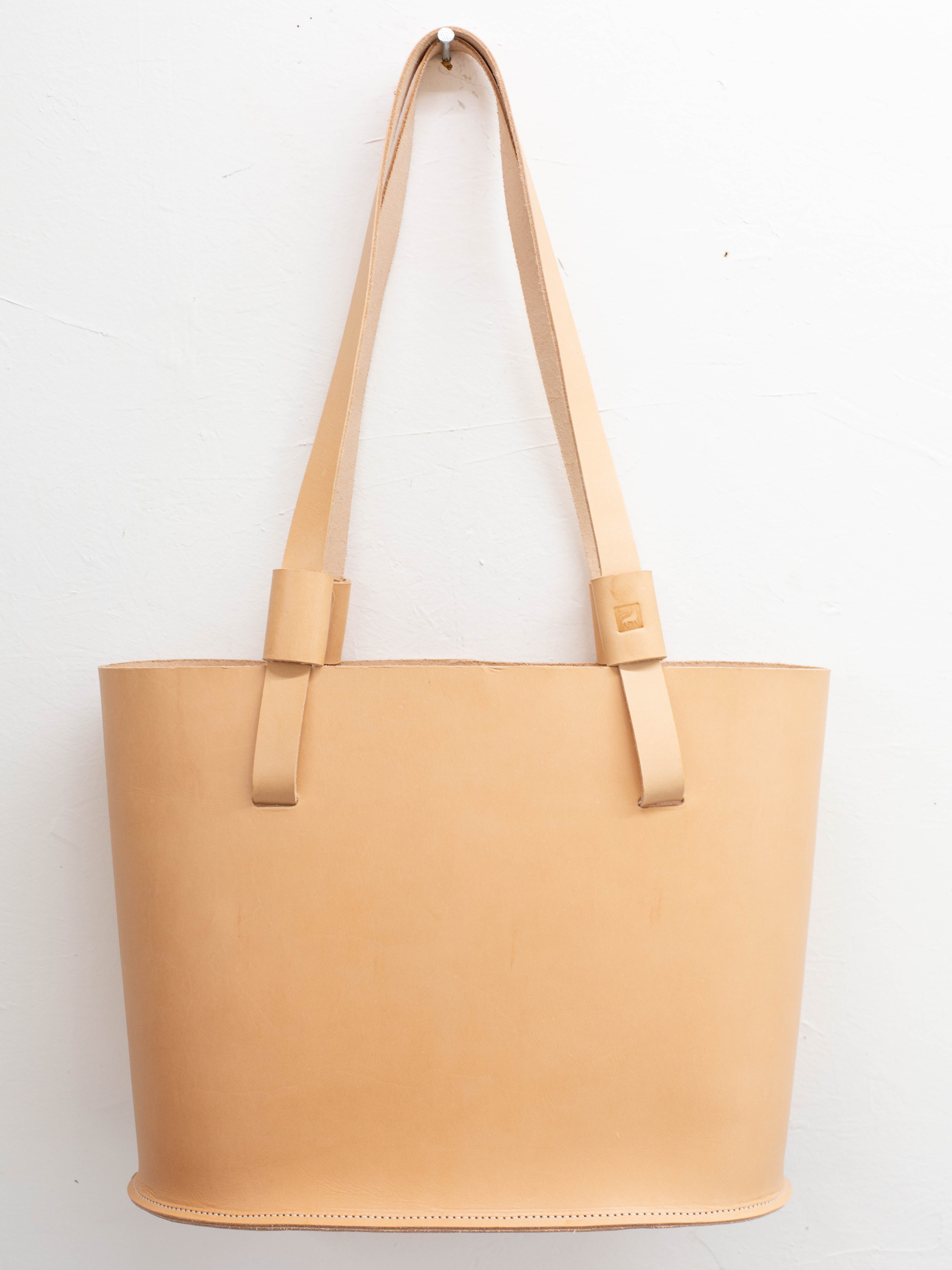 A leather tote bag, that is made from ethically sourced leather, in its natural undyed light tan color. 