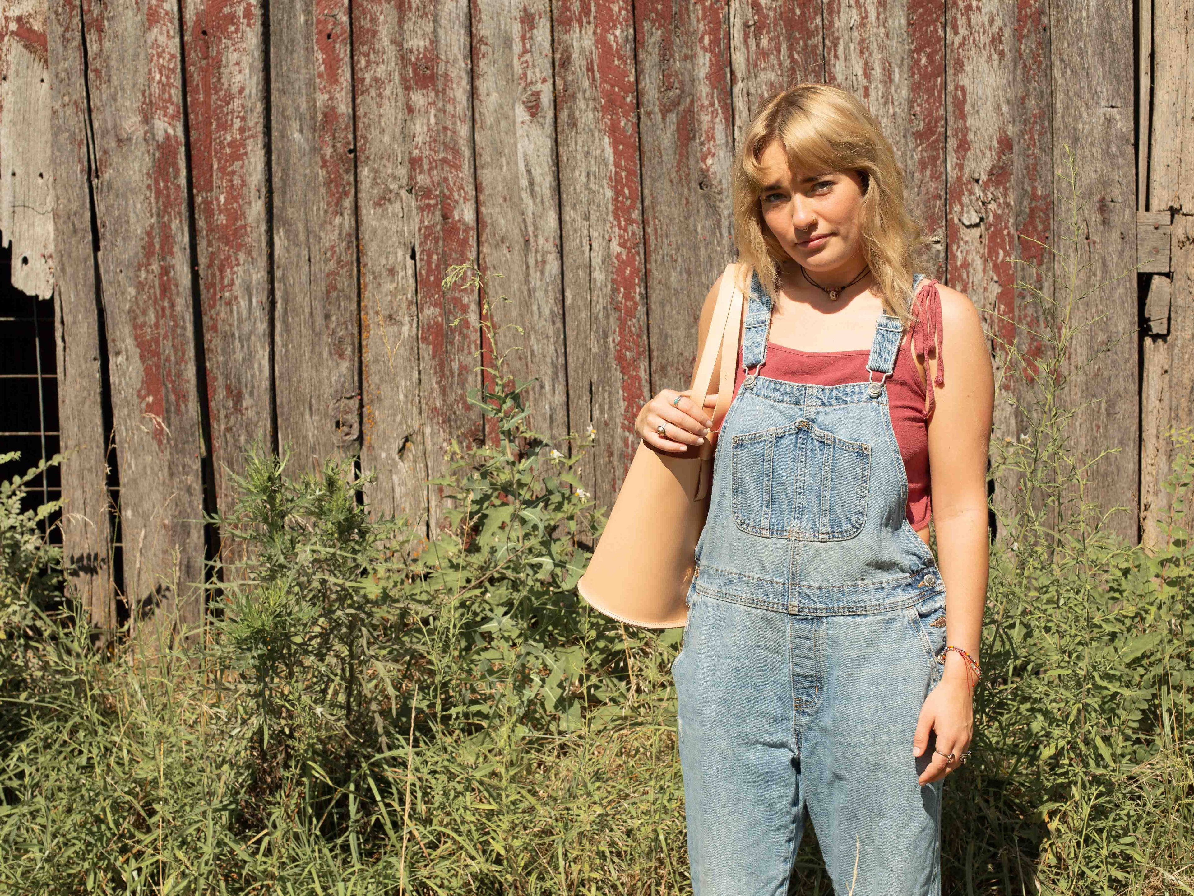 The smaller version of our veg tan tote bag "The Gatherer" is worn by a model showing the dimensions and look of the sustainable leather shoulder bag. 