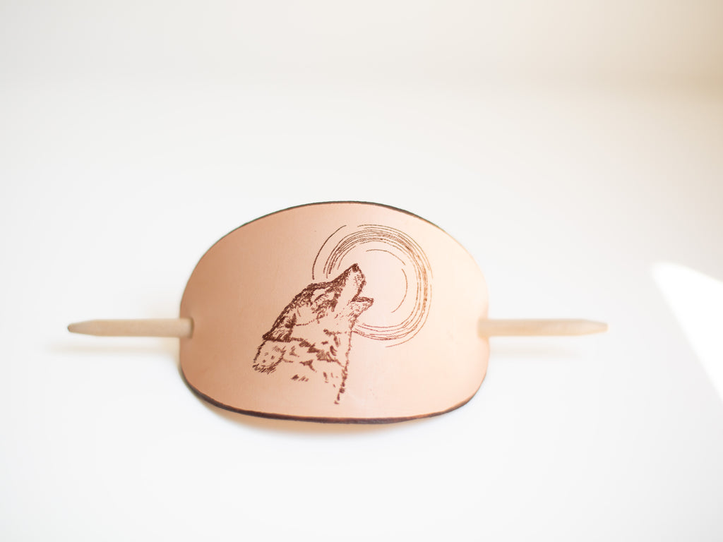 The large barrette made with sustainable leather features a laser engraving of a wolf howling at the moon. 
